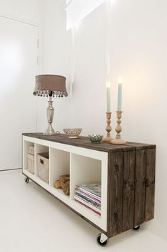 a table with two candles on it next to a lamp and some bookshelves