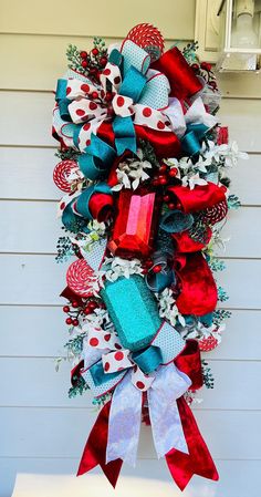 a red, white and blue christmas wreath hanging from the side of a house with presents on it