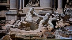 two statues in front of a fountain with water