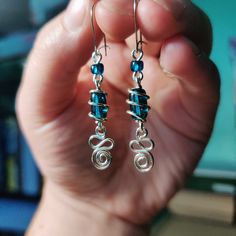 a person holding up some kind of blue beaded earrings in their hand with the other hand