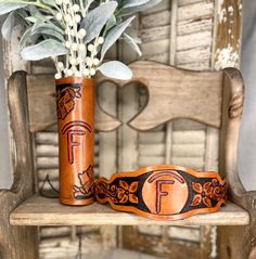 two vases with flowers in them sitting on a wooden chair next to a plant