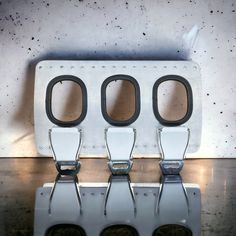 three white seats with holes in them sitting on a counter top next to a wall