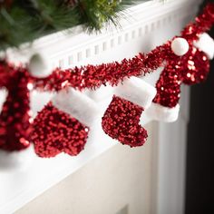 red and white christmas decorations hanging from a mantel