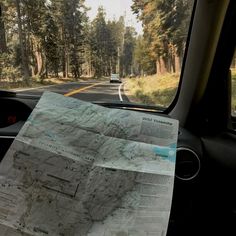 a map sitting on the dashboard of a car with trees in the backgroud