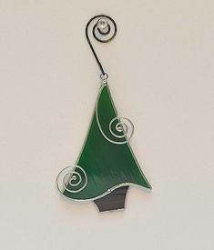 a green glass christmas tree ornament hanging from a hook on a white wall