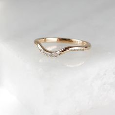 a gold wedding band with three diamonds on the side, sitting on a white surface