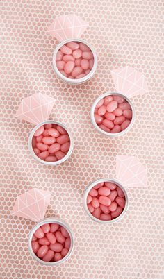 four small white bowls filled with pink candy