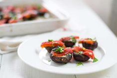 small stuffed mushrooms with tomato sauce on a white plate