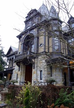 an old stone house with lots of windows and balconies on the front porch