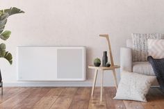 an air conditioner sitting on top of a wooden floor next to a white couch