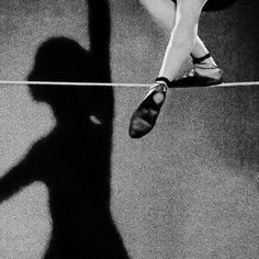 the shadow of a woman's legs and shoes on a rope