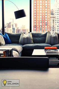 a living room filled with furniture and a large window covered in windowsills next to tall buildings