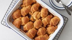 a casserole dish filled with baked goods on top of a cooling rack next to a cup of coffee