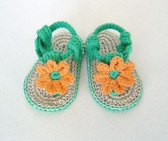 a pair of crocheted baby shoes with flowers on the front and bottom, sitting on a white surface