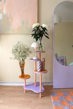 a mirror and some vases with flowers in them on a table next to a wall