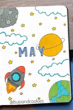 a notebook with the words may written on it and an image of a rocket ship