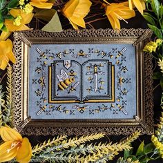 a cross - stitch book with bees and flowers in the background, surrounded by yellow flowers