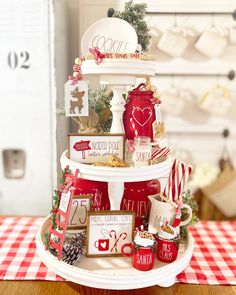 a three tiered christmas cake with red and white decorations on the top, surrounded by other holiday items