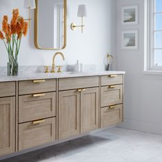 a bathroom with two sinks, mirrors and flowers in vases on the counter top