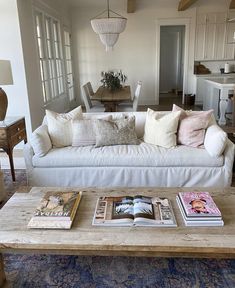 a living room filled with white furniture and lots of pillows on top of it's couch