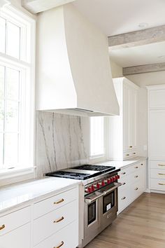 a stove top oven sitting inside of a kitchen next to white cabinets and counter tops