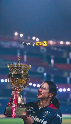 a woman holding up a trophy on top of a field