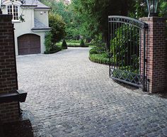 an iron gate leads into a brick driveway