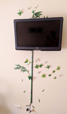 a flat screen tv mounted to the side of a wall with butterflies flying around it