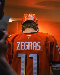 a man in an orange jersey is holding a cell phone