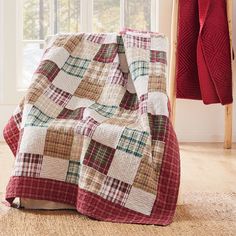 a red and white blanket sitting on top of a wooden floor next to a window