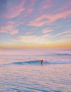 a person riding a wave on top of a surfboard in the ocean at sunset