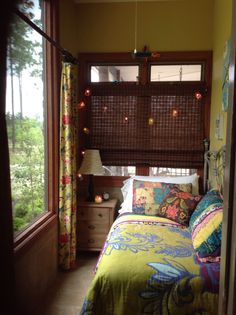 a bed sitting in a bedroom next to a window with blinds on the windowsill