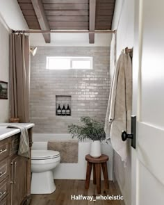 a white toilet sitting in a bathroom next to a wooden counter top under a window