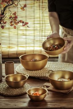 a person is holding a bowl with food in it on a table next to other bowls