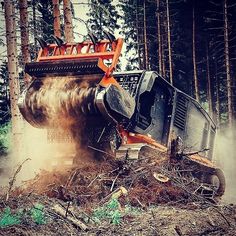 an orange and black truck driving through a forest filled with lots of dirt on top of it's wheels