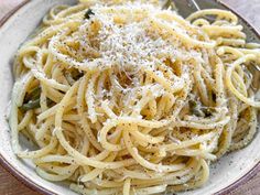 a white bowl filled with pasta and parmesan cheese on top of a wooden table