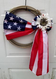 a wreath with an american flag ribbon and a flower on the front door for memorial day