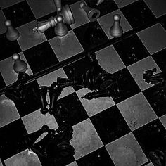 black and white photograph of chess pieces on a checkerboard floor with one pawn missing