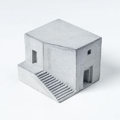 a small house made out of concrete with stairs leading up to the roof and door