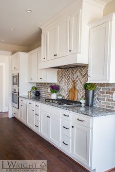 a kitchen with white cabinets and marble counter tops