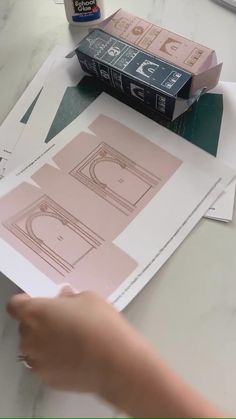 a person is cutting out some paper on top of a table with scissors and glue