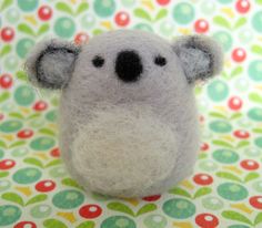 a small stuffed koala bear sitting on top of a colorful table cloth with circles around it