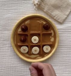 a person holding a plate with chocolates in it on a white table cloth next to a napkin