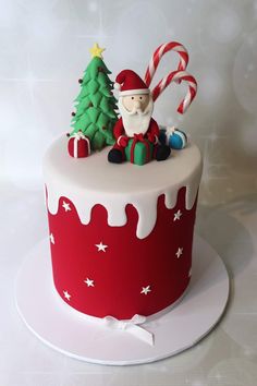 a decorated christmas cake sitting on top of a white plate with candy canes and a santa clause