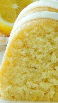 a slice of cake with white frosting and lemon wedges