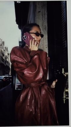 a woman in a leather coat talking on a cell phone