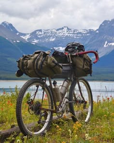 a bicycle parked next to a lake with mountains in the background