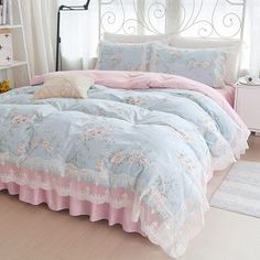 a bed with pink and blue comforters in a bedroom next to a white window