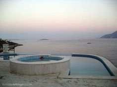 an empty swimming pool in front of the ocean