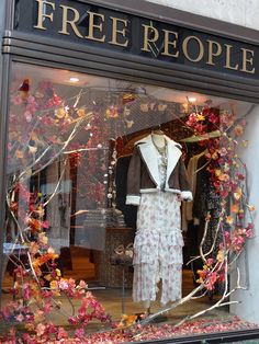 a storefront window with mannequins and flowers in the window display case